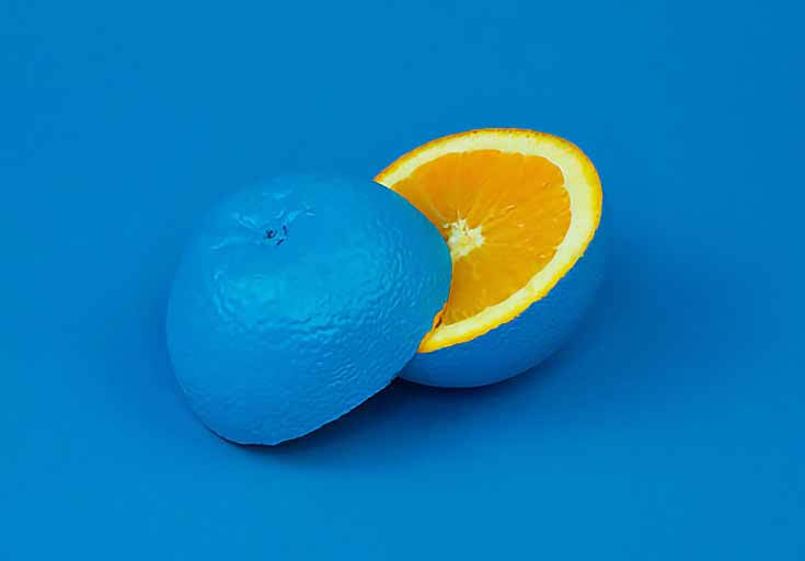 Photo of an orange painted blue, cut in half to show the orange center