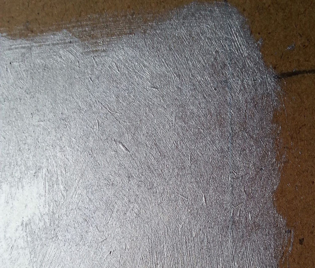 Detail photo of brushwork in silver paint on board