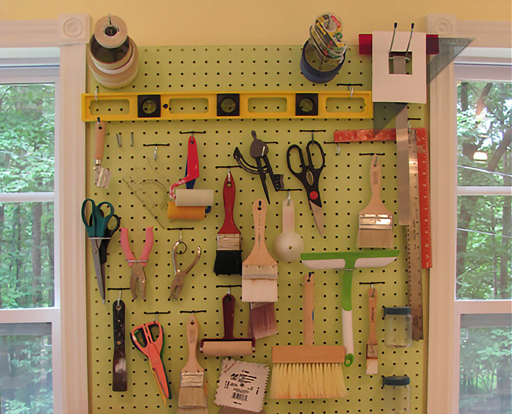 Art studio pegboard wall with various art tools hanging from it