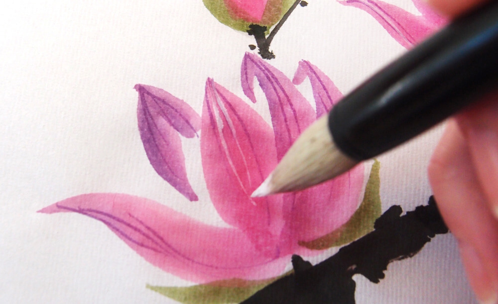 Brush dipped in white gouache painting delicate veins on a Magnolia blossom