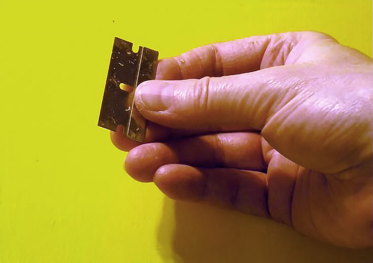 Artist holding a razor blade to check if oil paint layer is dry