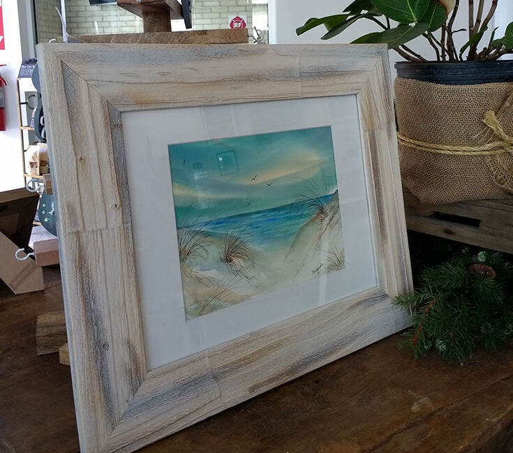 Framed watercolor painting of coastal dunes and ocean water