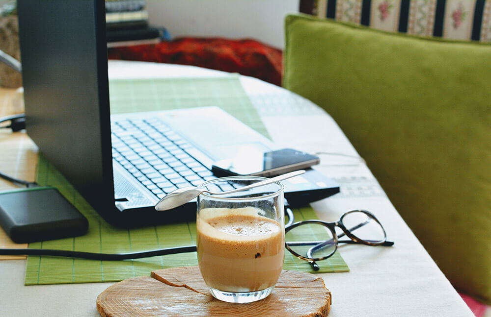 Coffee and laptop in front of a comfy chair at home