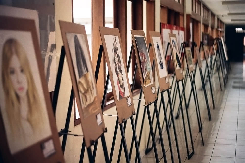 A row of artist easels lined up with student artwork on display