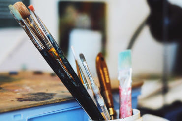 Disorganized artist studio with paintbrushes in an old container